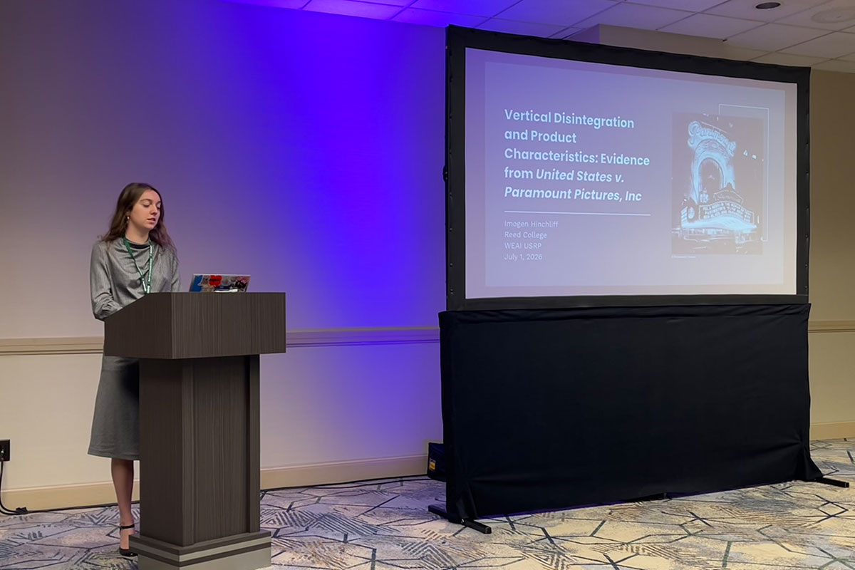 A woman stands at a podium presenting her research.