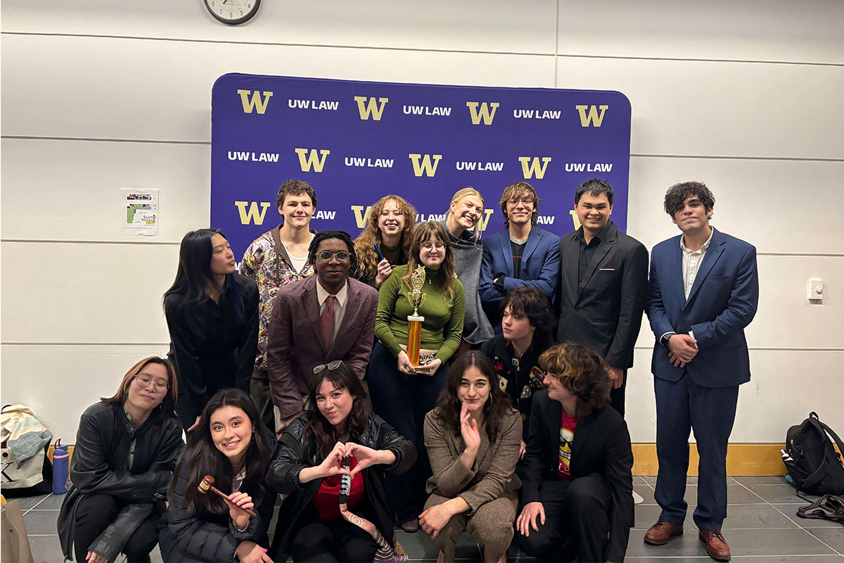 The Mock Trial team poses with a trophy in front of a UW Law backdrop at Regionals. 