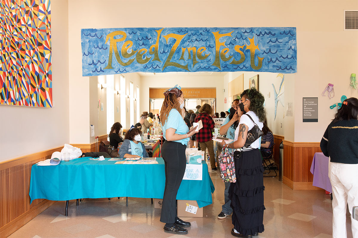 People gather and chat beneath a banner reading "Reed Zine Fest."