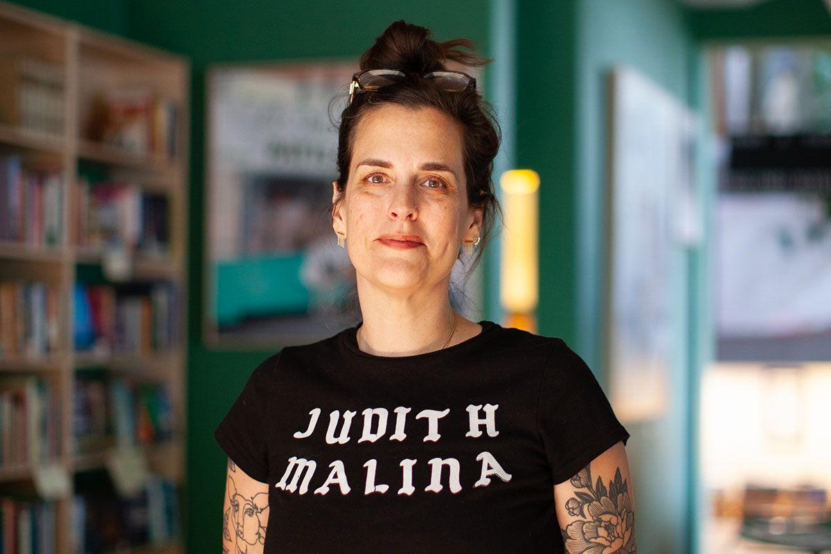 Photo of Kate Bredeson wearing a black shirt with the words "Judith Malina" screenprinted on it in white lettering.