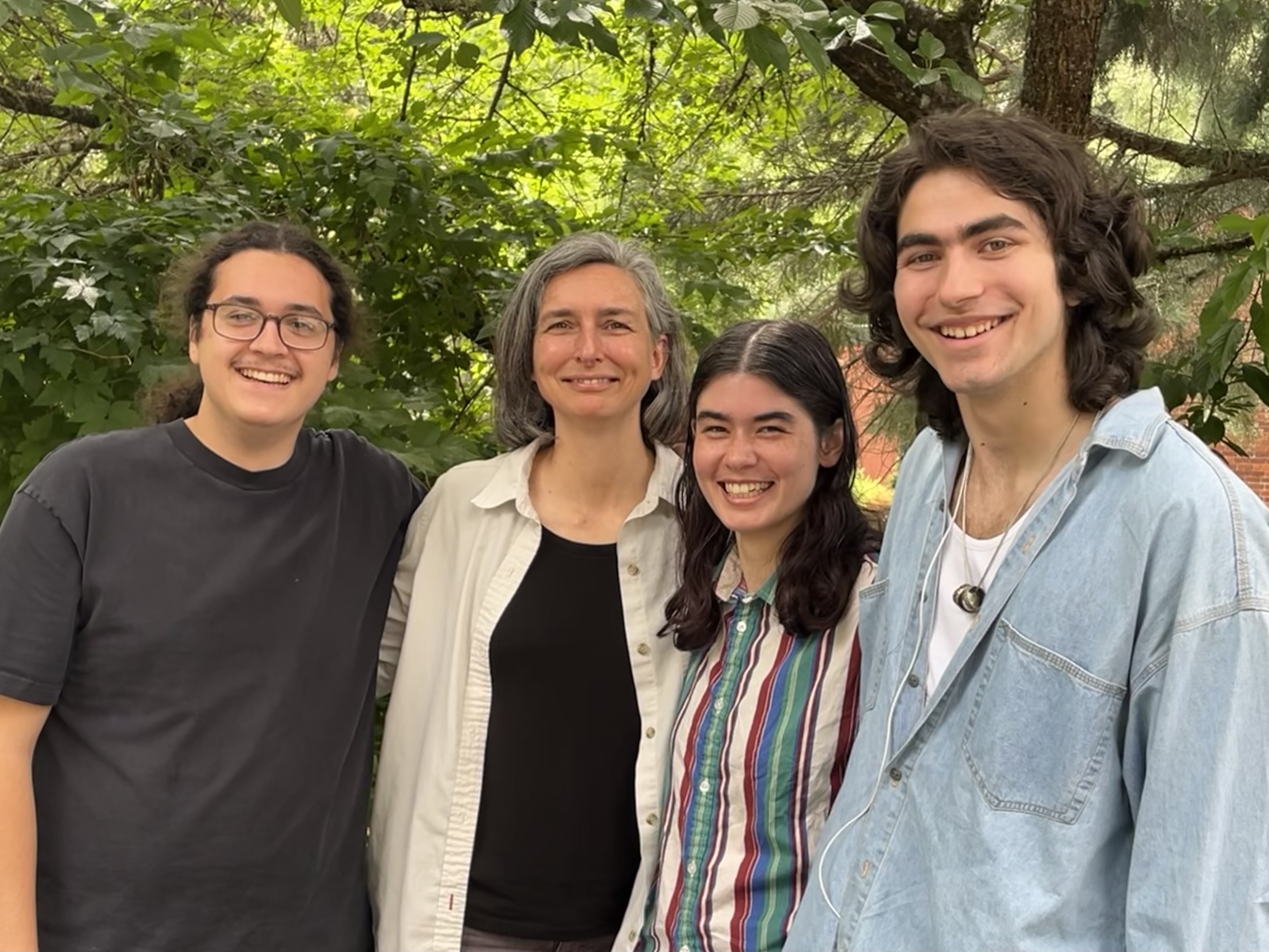 The summer research team outdoors on the Reed campus, standing behind and sitting on a bench.