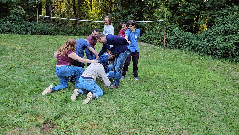 A clump of students piling on top of each other on a grassy field
