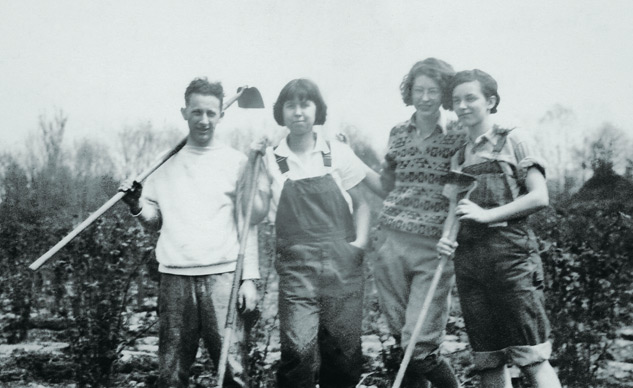 Black and White photo with four students carrying hoes.