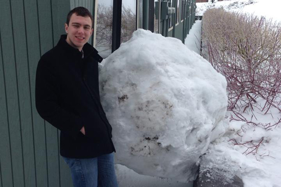 Theo Landsman &amp;#8217;16 stands next to the runaway 800-lb snowball that put a dent in his dorm room. Math majors were involved in constructing the icy myriahedron.
