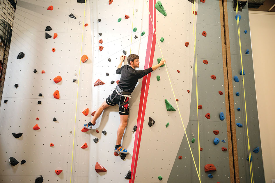 Michael Frazel '17 finds his route on the new climbing wall, which was installed as a part of sports center renovations. Photo By Christopher Onstott
