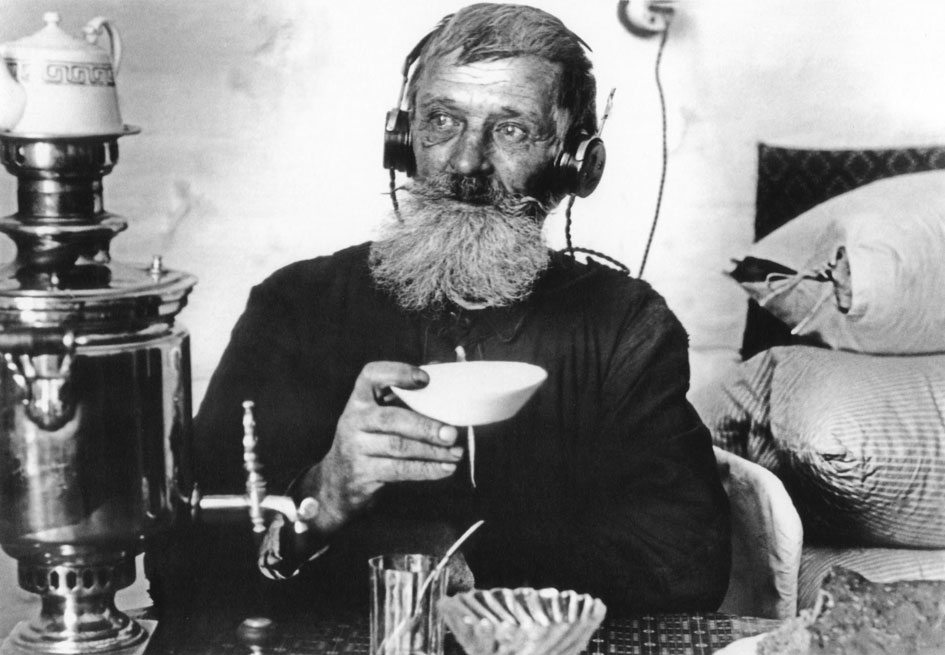 A Soviet worker sips tea from a samovar and listens to the radio in 1929.