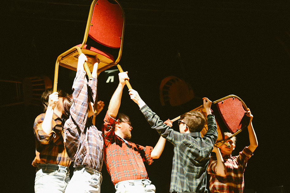 Students Hold Chairs on Stage