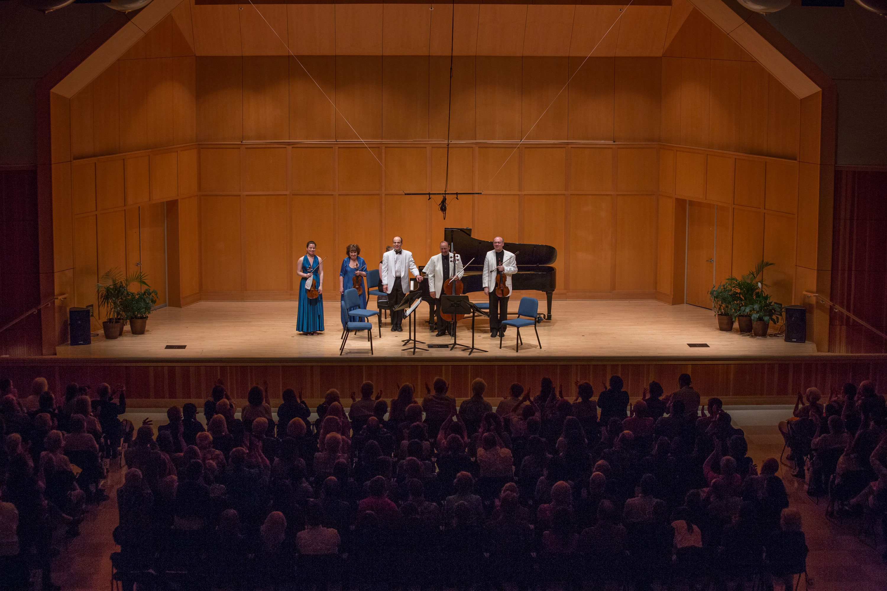 Five chamber players on stage with a grand piano