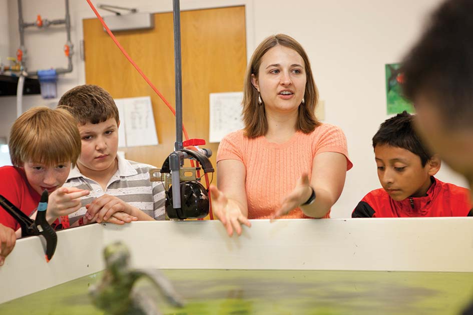 OPENING MINDS. Biology faculty administrative coordinator Kristy Gonyer &amp;#8217;10 talks to local gradeschoolers about the enduring mysteries of the fire-bellied toad (pictured blurrily in foreground).