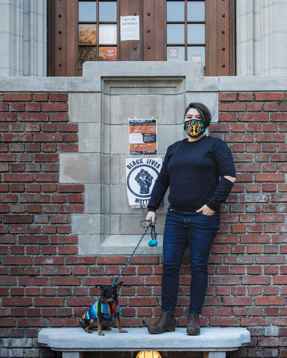 Professor Kelly Chacón in front of Eliot Hall with dog Devo