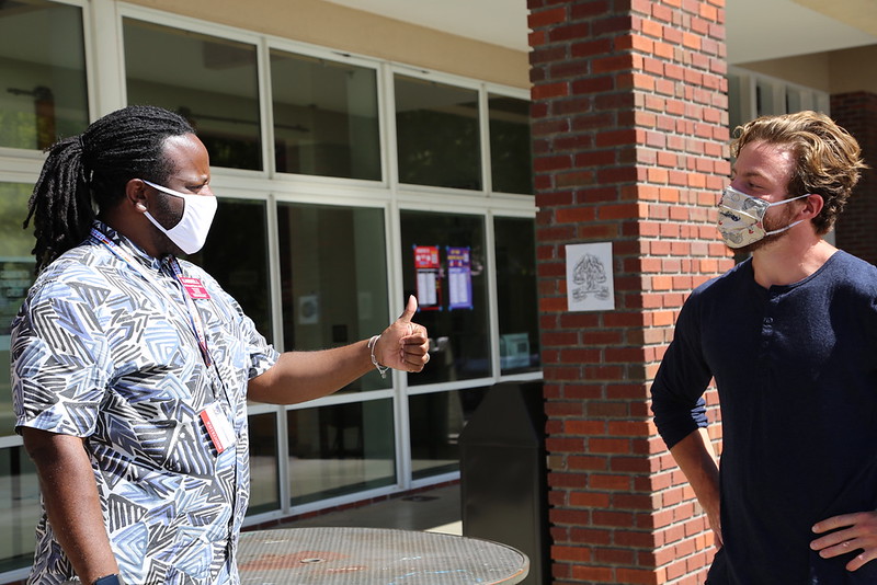 Photo of Karnell in a mask talking to a student in a mask