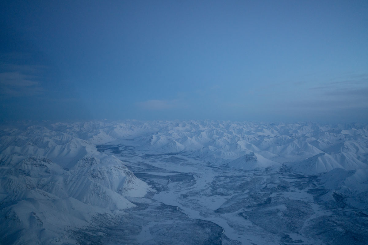 The expansive Chandalar River extends below as Lana flies from Fairbanks to Kaktovik. These wide river valleys are used by Alaskan pilots like roads to navigate within mountains, rivers defining the lowest and most hospitable terrain.