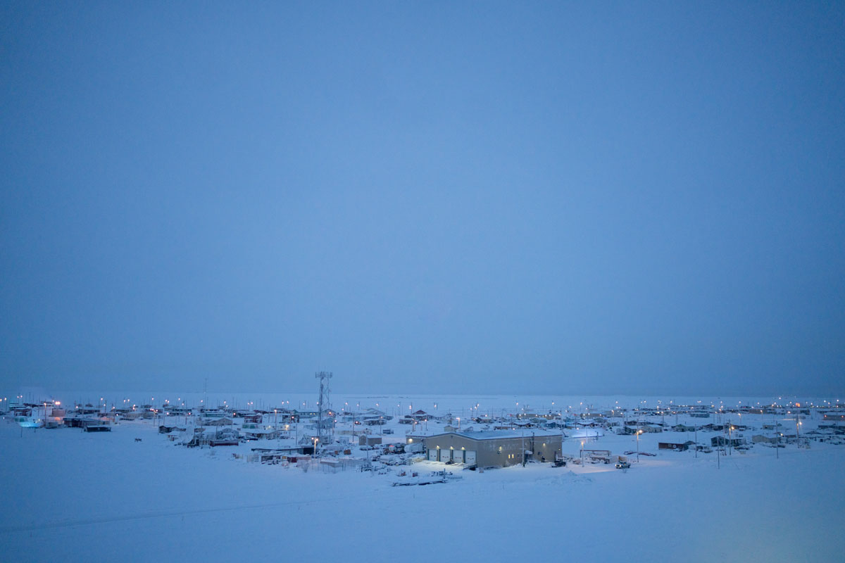The town of Utqiagvik (formerly known as Barrow) pictured a few days before the winter solstice. In Utqiagvik the sun sets on November 18th and rises again on January 23rd. The 67 days in between are lit by a few hours of indirect light, which illuminates the coastal plane upon which Utqiagvik lies. The Arctic Ocean can be seen beyond the lights of town in the background.