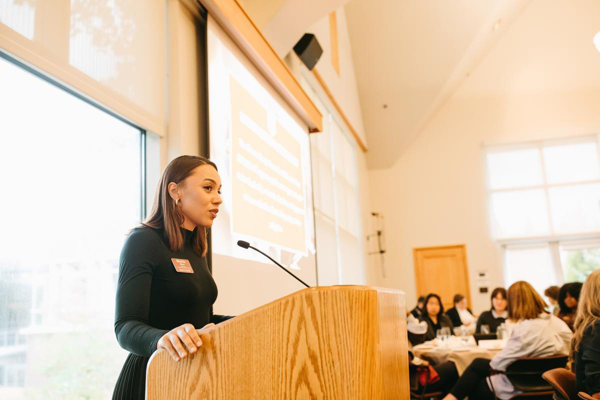 A woman speaks into a microphone at a podium.