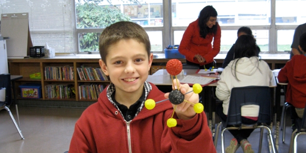 A student holds up a scientific model he has built.