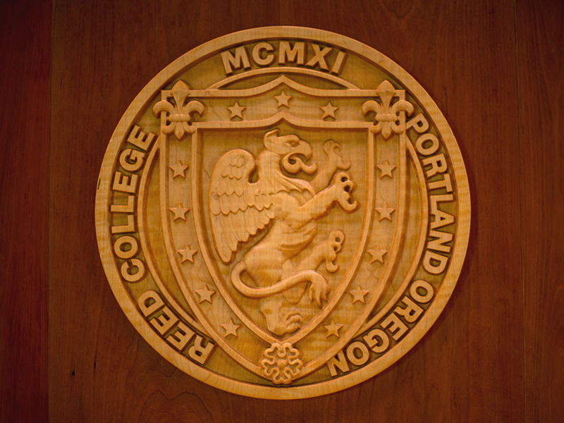 A carved wooden Reed College seal displayed on the front of a podium.