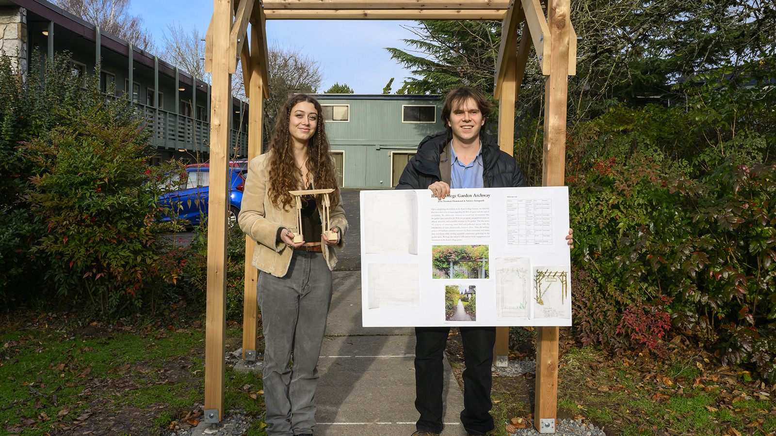 Two students presenting their design, in front of the arbor