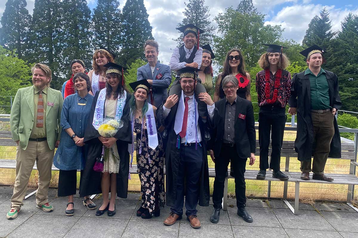Group of faculty and staff posing with graduating seniors in ceremonial robes